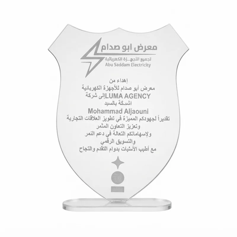 Shield-shaped clear acrylic award engraved in Arabic, presented by Abu Saddam Electricity to LUMA Agency in recognition of its work in digital marketing.