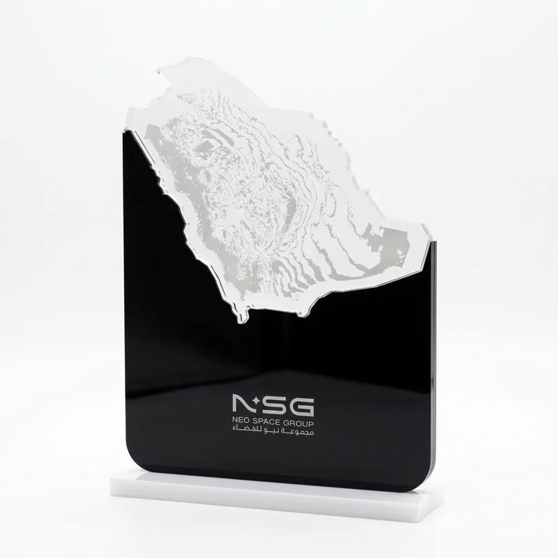 Black acrylic award topped with a frosted relief map of Saudi Arabia, the Neo Space Group logo etched on its face, standing on a white base.
